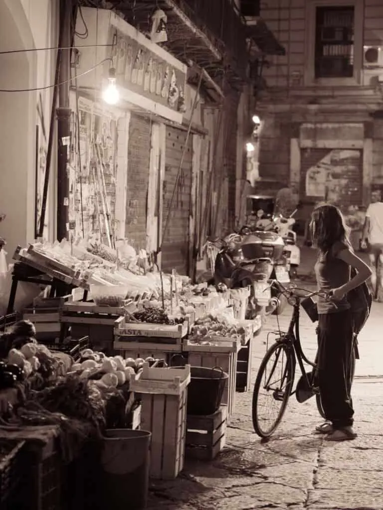 pair A cyclist pauses at a fruit stall in a Palermo street market