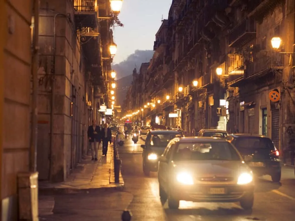 pair Evening traffic threading down a lamp-lit Palermo street
