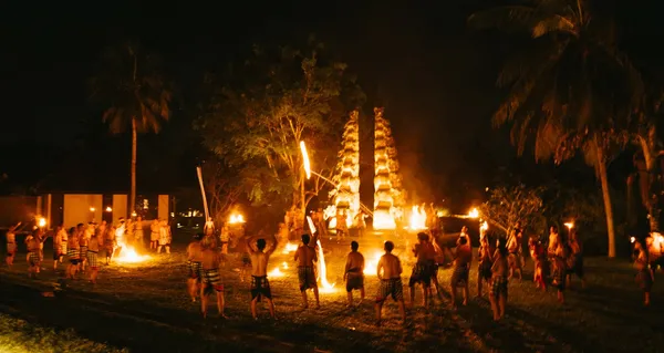 A night-time Kecak fire dance, rows of seated performers before a torch-lit temple gate, the tall shrines blazing behind.