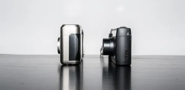 The Contax T2 and Ricoh GR1v film compacts standing side by side.