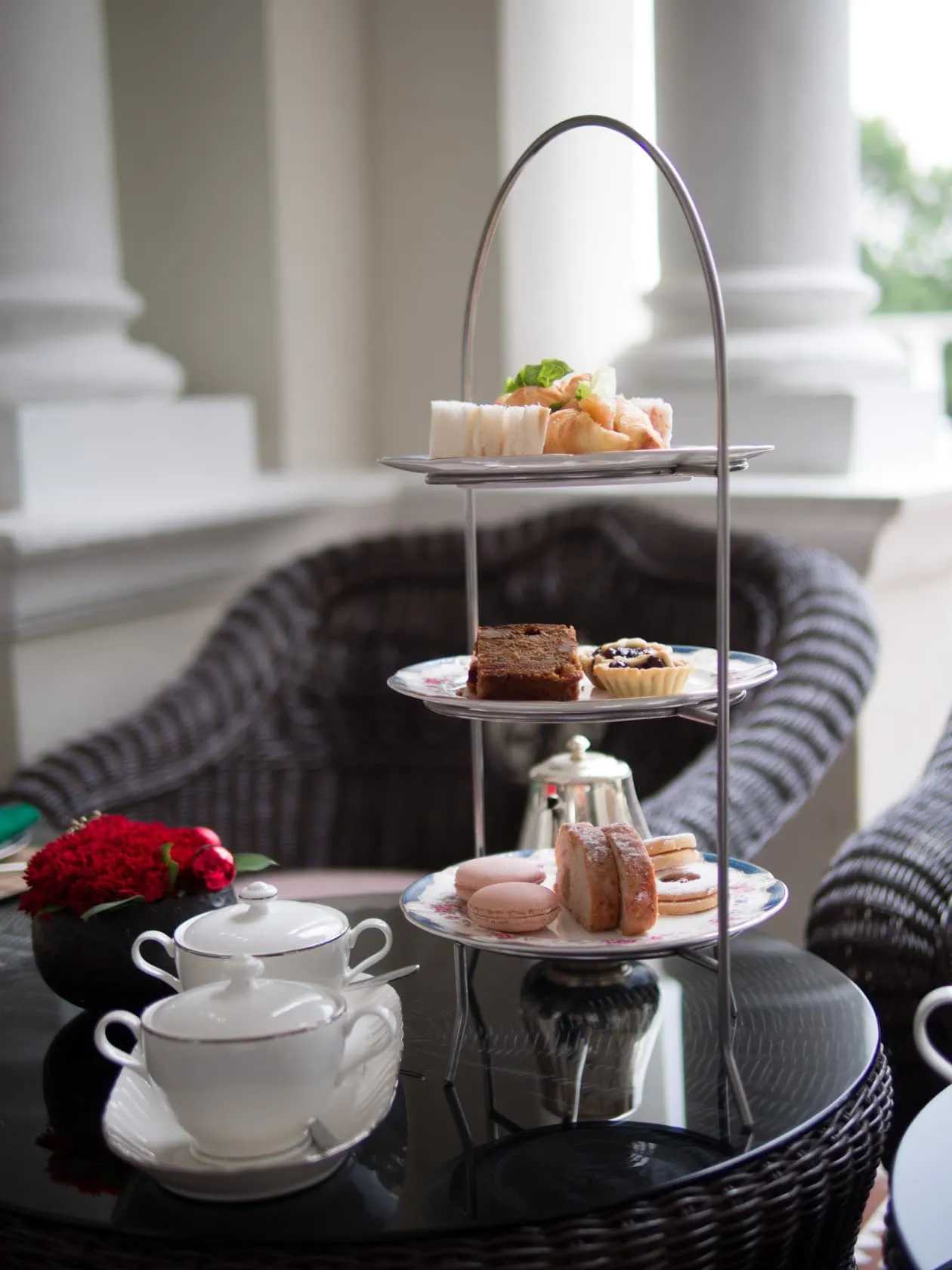 pair The full afternoon-tea stand on the veranda at Carcosa Seri Negara, silver teapot and floral china alongside